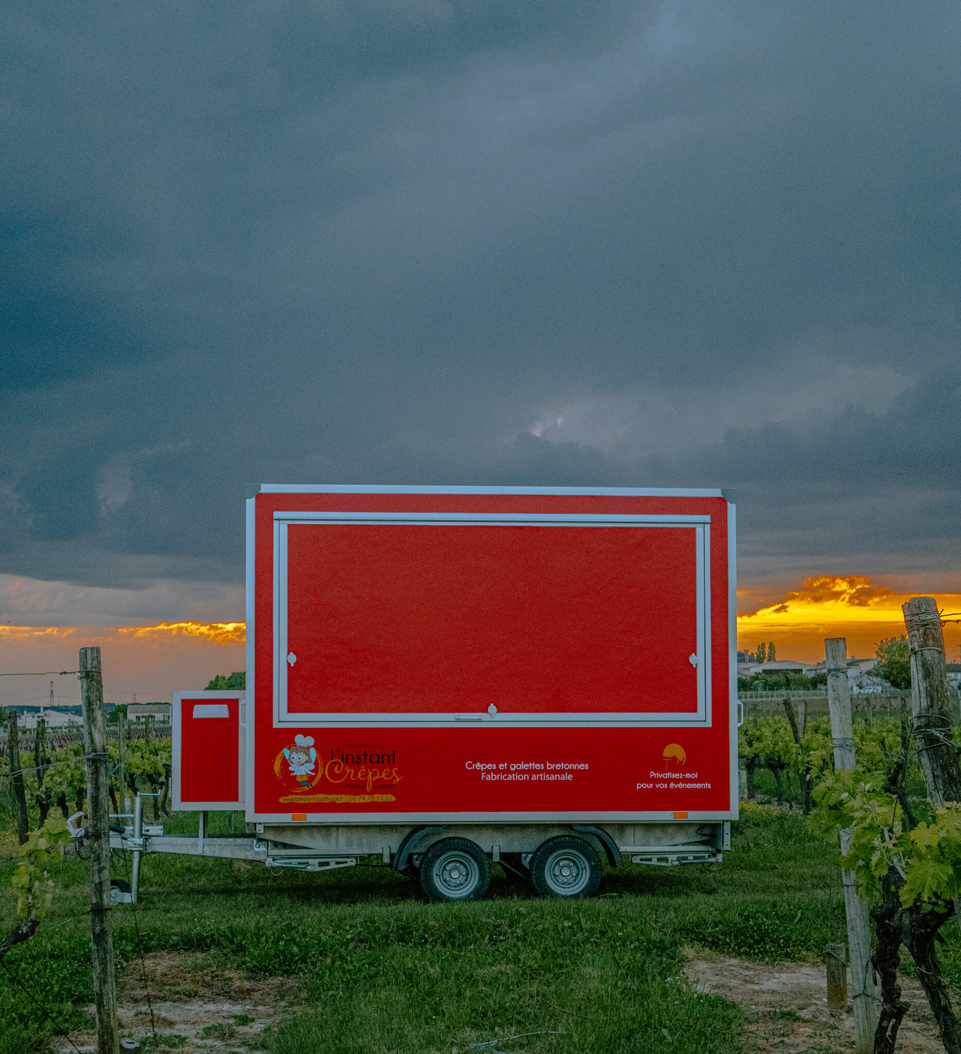 Camion rouge Instant Crêpes dans vignoble au crépuscule.